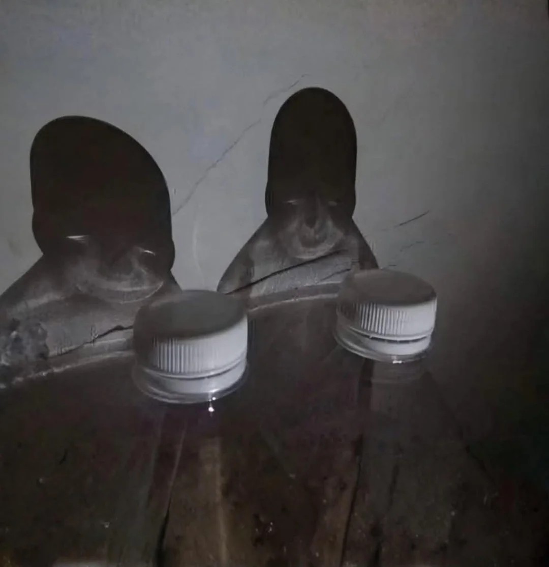 Two bottles with a shadow reflection of creepy kids